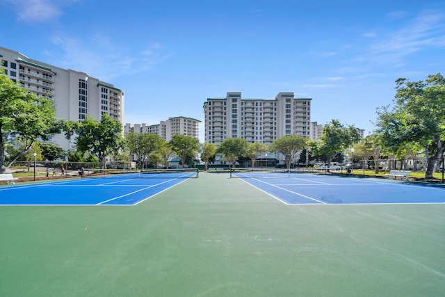 view of tennis court featuring a view of city and fence