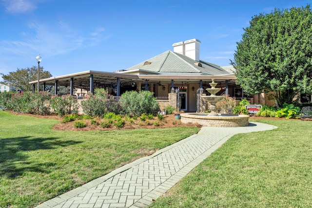 view of front of property featuring brick siding, a chimney, and a front yard