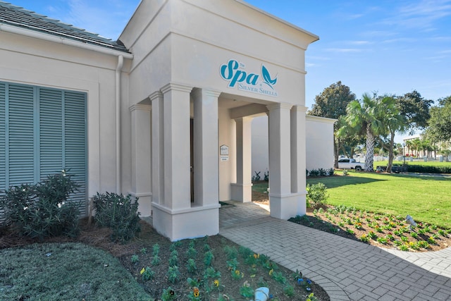 doorway to property with a lawn and stucco siding