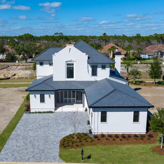 modern inspired farmhouse with decorative driveway, a front yard, and stucco siding