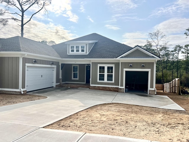 view of front facade with a shingled roof, concrete driveway, board and batten siding, and an attached garage