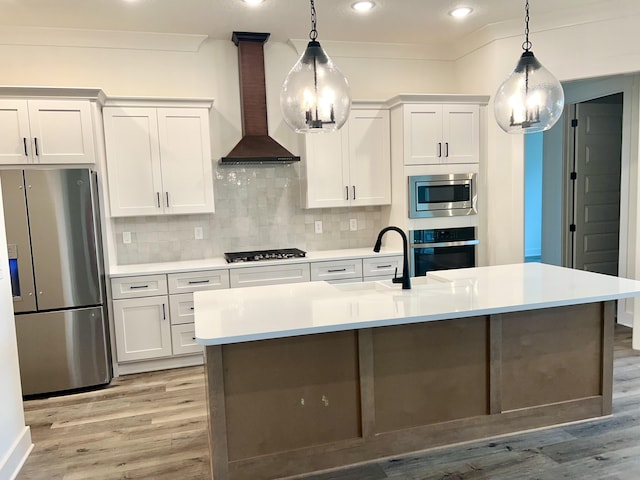 kitchen with stainless steel appliances, light countertops, light wood-style flooring, decorative backsplash, and wall chimney exhaust hood