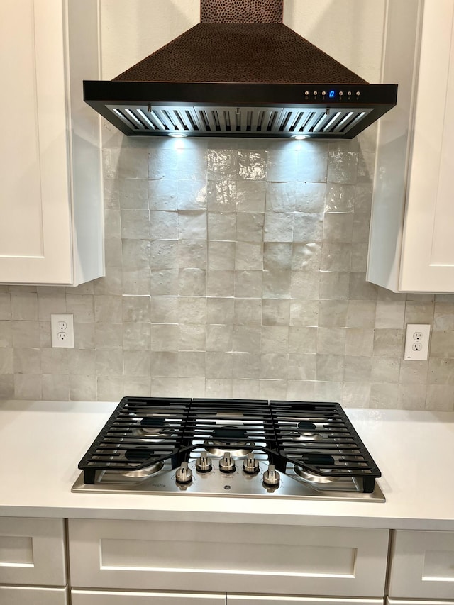 details featuring stainless steel gas cooktop, light countertops, custom range hood, backsplash, and white cabinetry