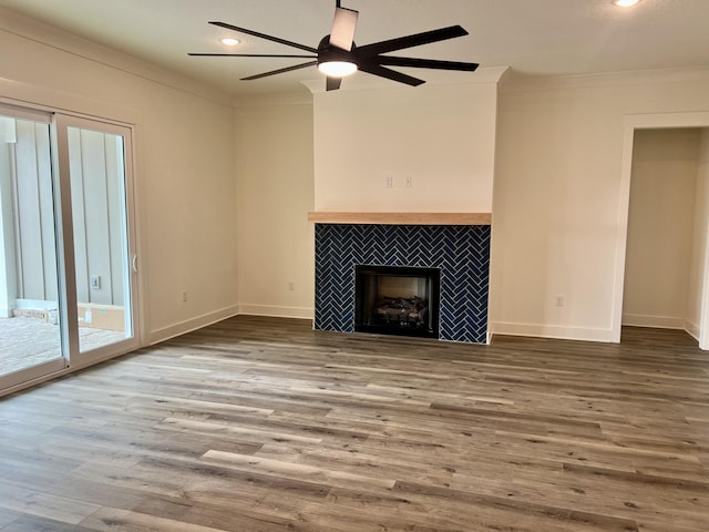 unfurnished living room featuring baseboards, ornamental molding, wood finished floors, a fireplace, and recessed lighting