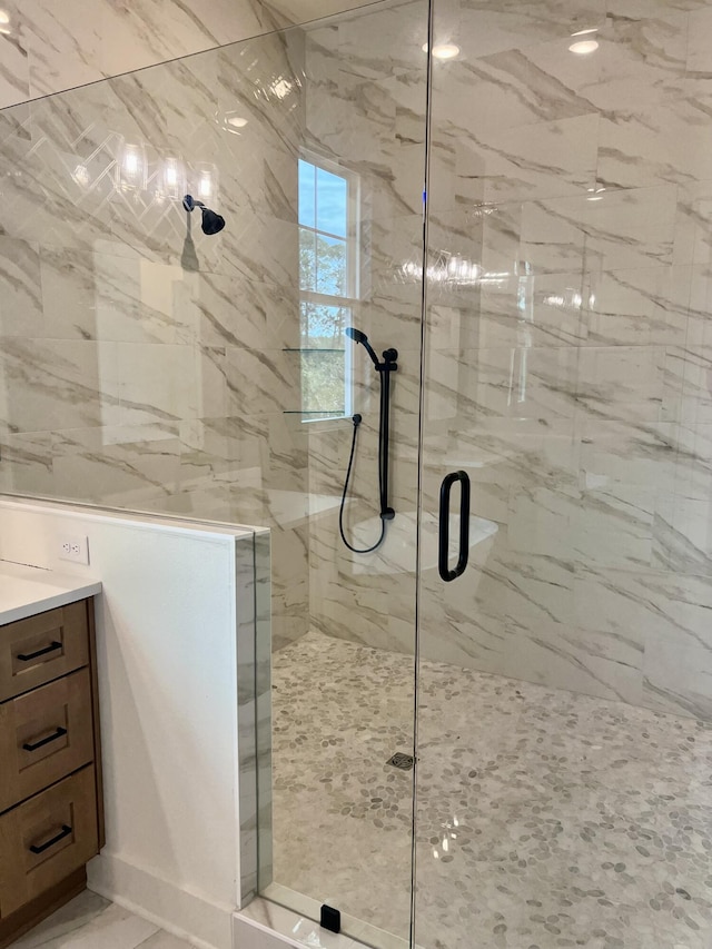 full bathroom with a marble finish shower and vanity