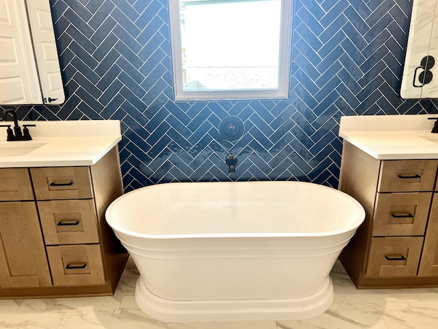 bathroom featuring marble finish floor, a soaking tub, vanity, and tile walls