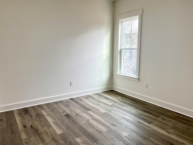 spare room featuring baseboards and dark wood-style flooring