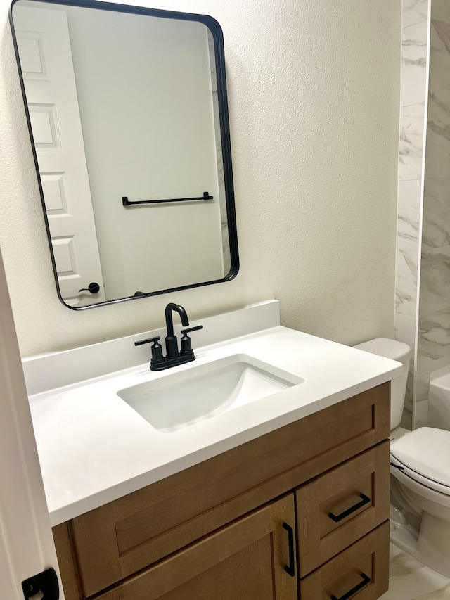 full bath with a textured wall, toilet, marble finish floor, walk in shower, and vanity