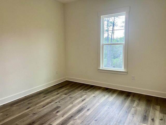 unfurnished room with a wealth of natural light, dark wood finished floors, and baseboards