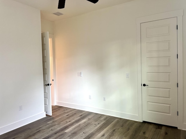 spare room featuring a ceiling fan, baseboards, visible vents, and dark wood-type flooring