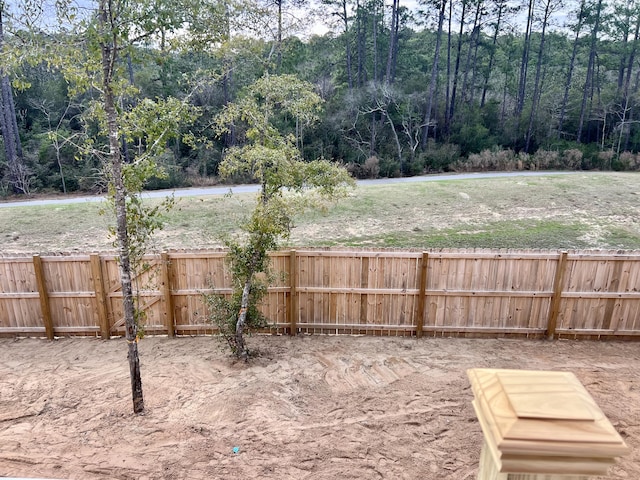 view of yard with fence and a view of trees