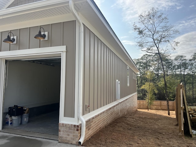 view of side of home with board and batten siding, fence, and a garage