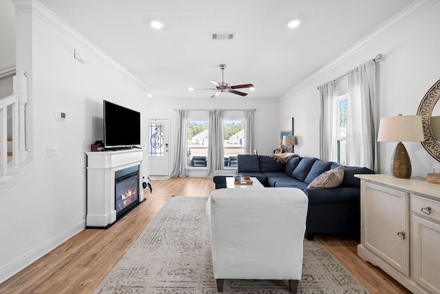 living room featuring crown molding, a wealth of natural light, and light wood-type flooring