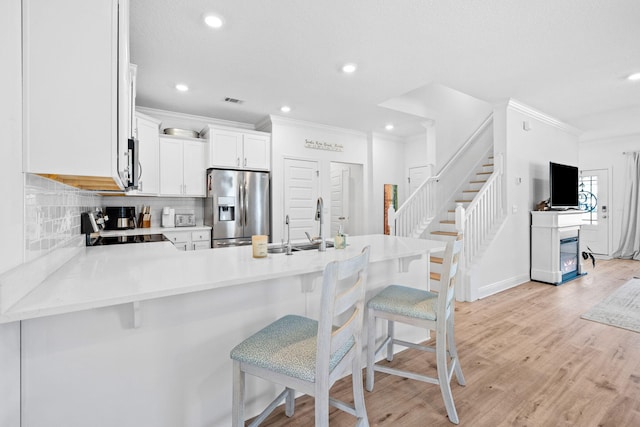 kitchen featuring a breakfast bar area, stainless steel appliances, kitchen peninsula, and white cabinets