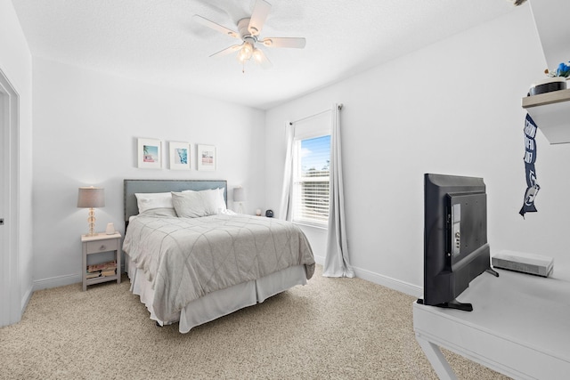 bedroom featuring ceiling fan, light colored carpet, and a textured ceiling