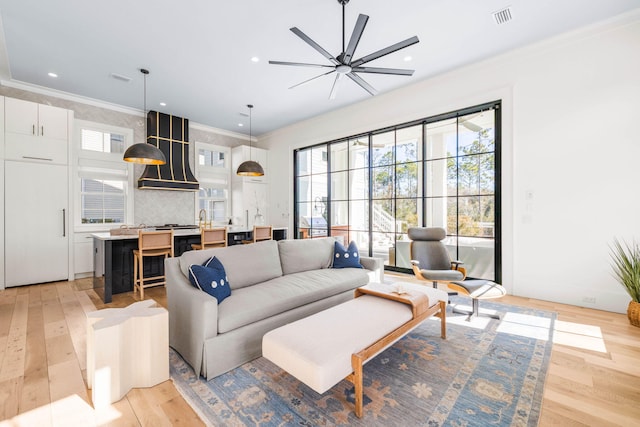 living room featuring crown molding, ceiling fan, and light wood-type flooring