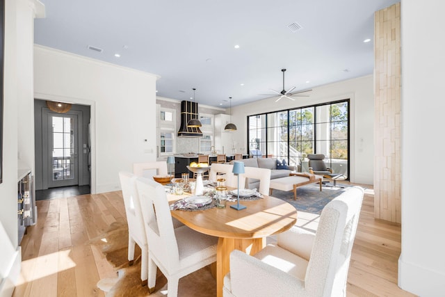 dining space with ornamental molding, a healthy amount of sunlight, and light wood-type flooring