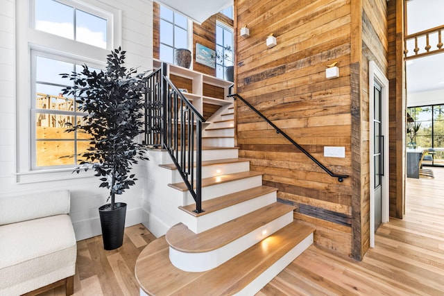 stairs featuring a towering ceiling, hardwood / wood-style floors, and wooden walls