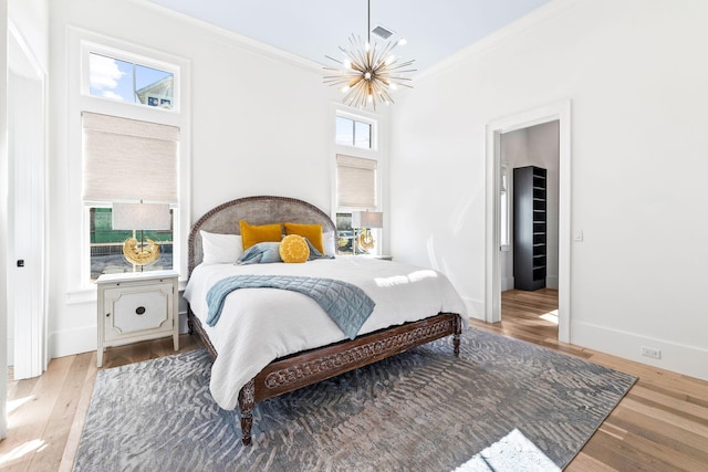 bedroom with hardwood / wood-style flooring, ornamental molding, and a notable chandelier