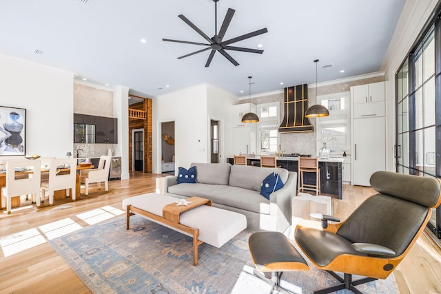 living room with crown molding, a wealth of natural light, and light hardwood / wood-style flooring