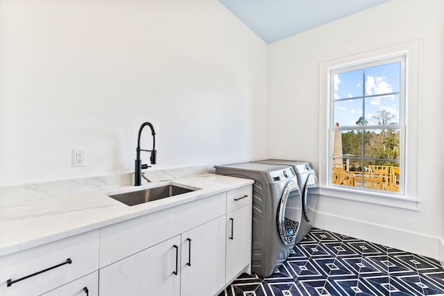 clothes washing area with cabinets, washer and dryer, and sink