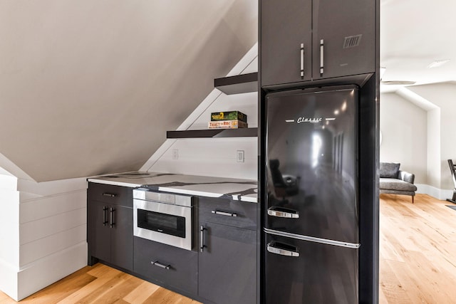 kitchen featuring vaulted ceiling, light wood-type flooring, and black appliances