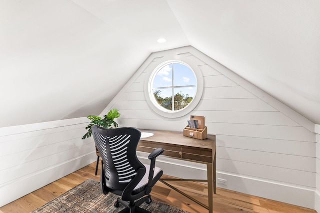 office space featuring lofted ceiling, hardwood / wood-style floors, and wooden walls