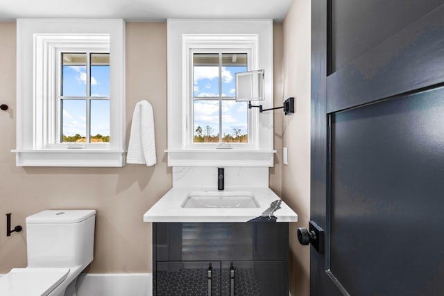 bathroom featuring vanity, plenty of natural light, and toilet