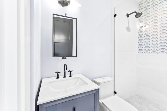 bathroom with vanity, a tile shower, and toilet