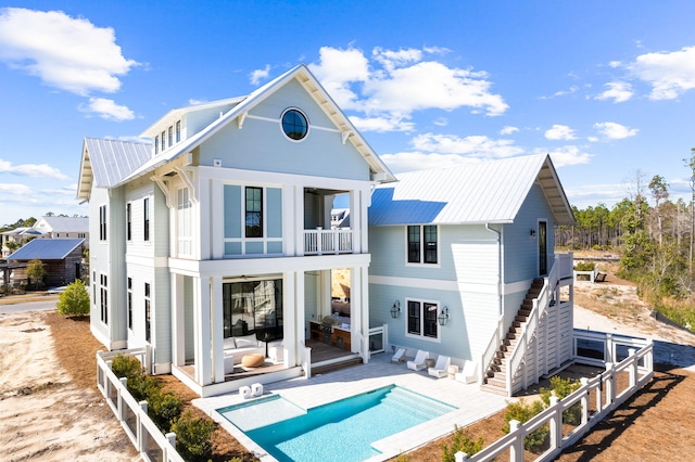 rear view of house with a fenced in pool, a balcony, and a patio area