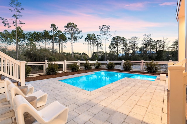 pool at dusk featuring a patio area