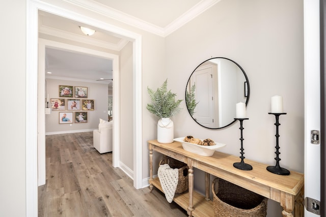 corridor featuring light wood-type flooring, crown molding, and baseboards