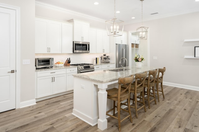 kitchen with an inviting chandelier, crown molding, appliances with stainless steel finishes, and a sink