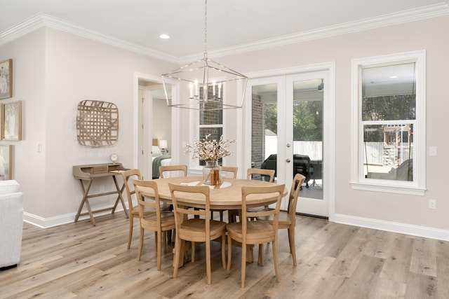 dining space featuring an inviting chandelier, french doors, light wood-style floors, and ornamental molding