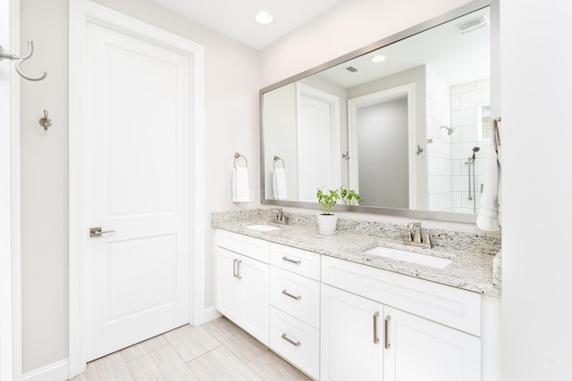 full bath featuring a sink, visible vents, double vanity, and a tile shower