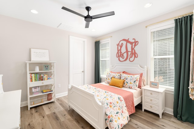 bedroom featuring multiple windows, light wood-style floors, and baseboards