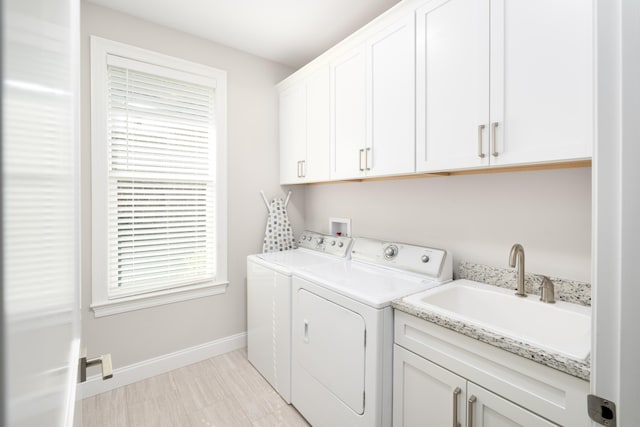 laundry area featuring cabinet space, washer and dryer, baseboards, and a sink