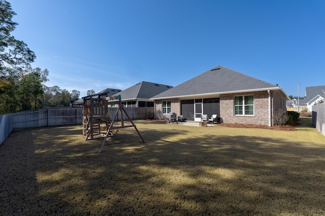 rear view of house with a patio area, brick siding, a fenced backyard, and a playground