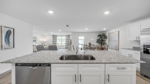 kitchen featuring sink, appliances with stainless steel finishes, a kitchen island with sink, light hardwood / wood-style floors, and white cabinets