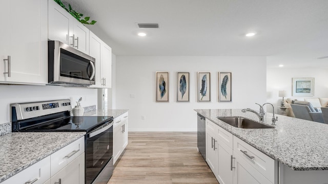 kitchen featuring sink, stainless steel appliances, white cabinets, and light stone countertops