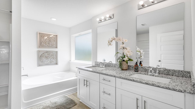 bathroom with hardwood / wood-style flooring, vanity, and a washtub