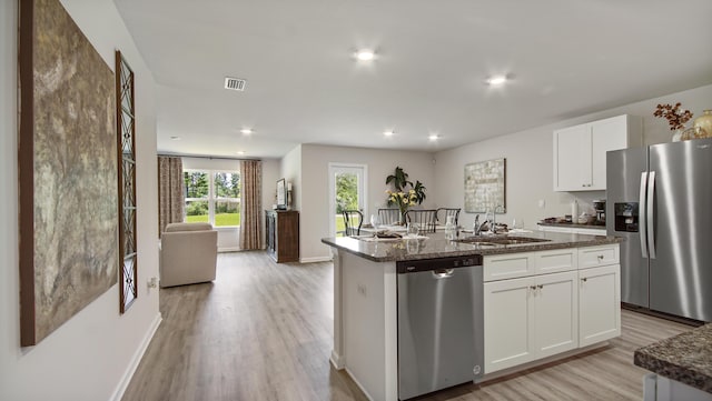 kitchen with visible vents, light wood finished floors, a sink, stainless steel appliances, and white cabinets