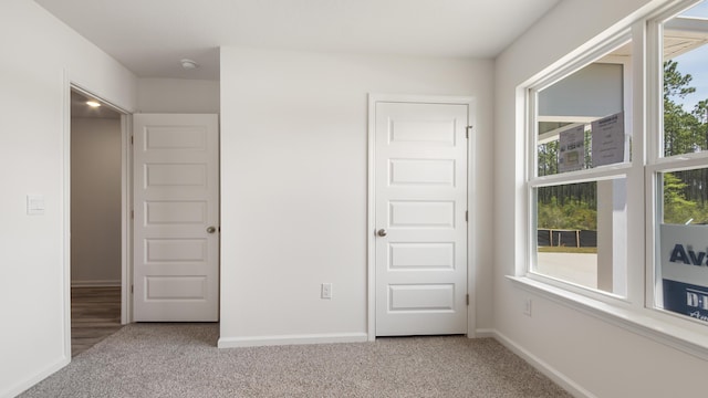 unfurnished bedroom with baseboards, multiple windows, and carpet floors