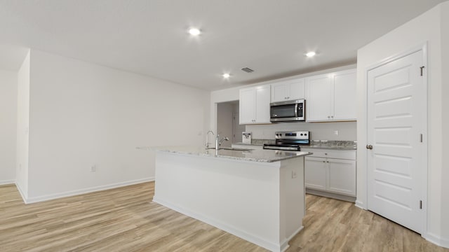 kitchen featuring a sink, a center island with sink, stainless steel appliances, white cabinets, and light wood-type flooring