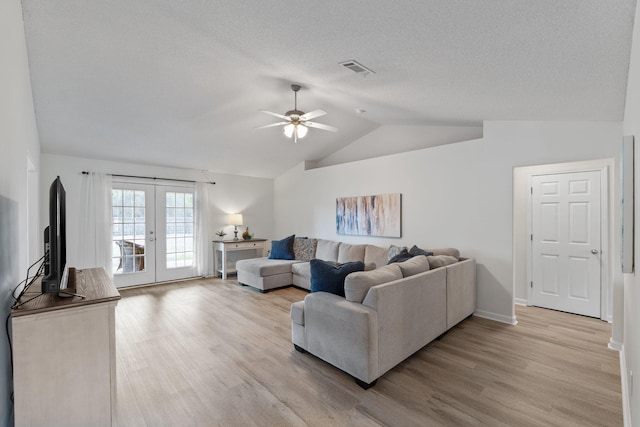 living room with lofted ceiling, light wood-type flooring, ceiling fan, a textured ceiling, and french doors