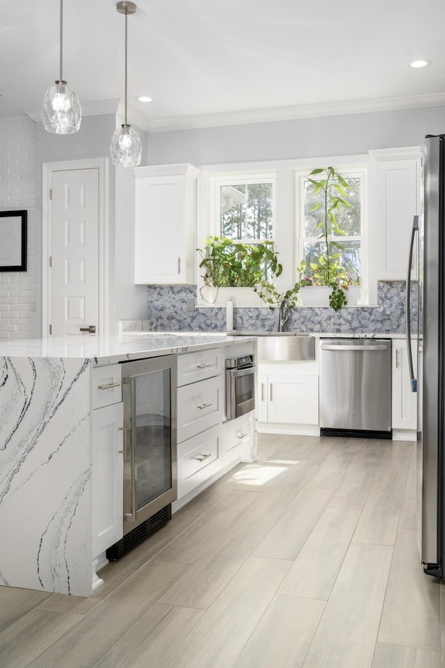 kitchen featuring white cabinetry, decorative light fixtures, beverage cooler, and appliances with stainless steel finishes