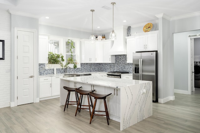 kitchen featuring sink, white cabinetry, hanging light fixtures, a kitchen island, and stainless steel appliances