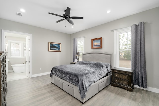 bedroom with ensuite bathroom, a fireplace, ceiling fan, and light hardwood / wood-style flooring