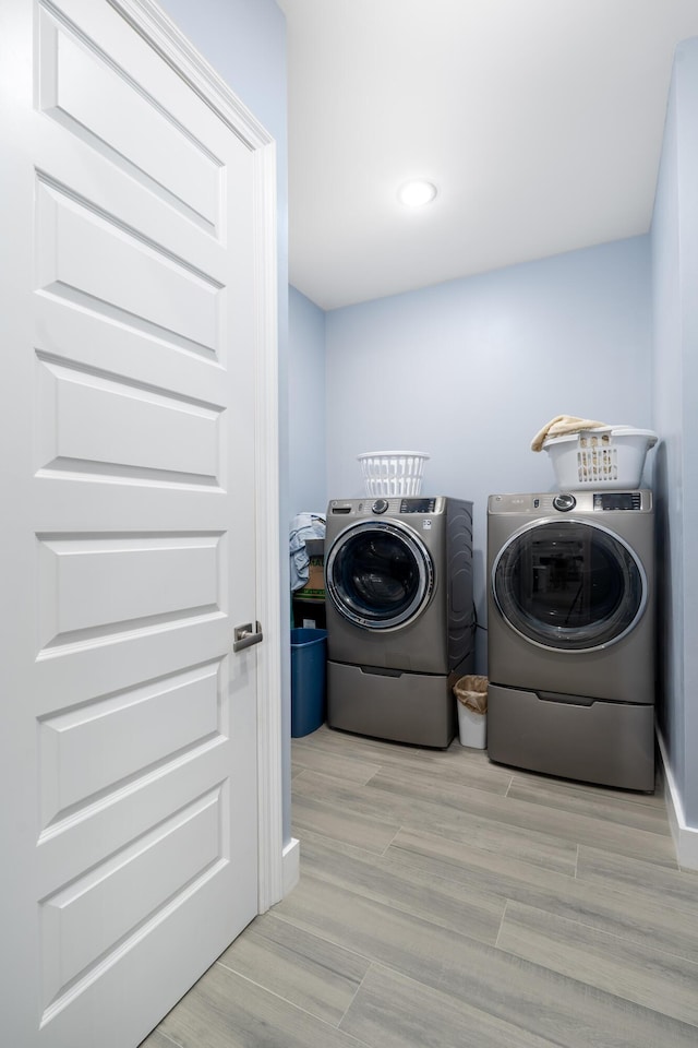 clothes washing area with separate washer and dryer and light hardwood / wood-style flooring