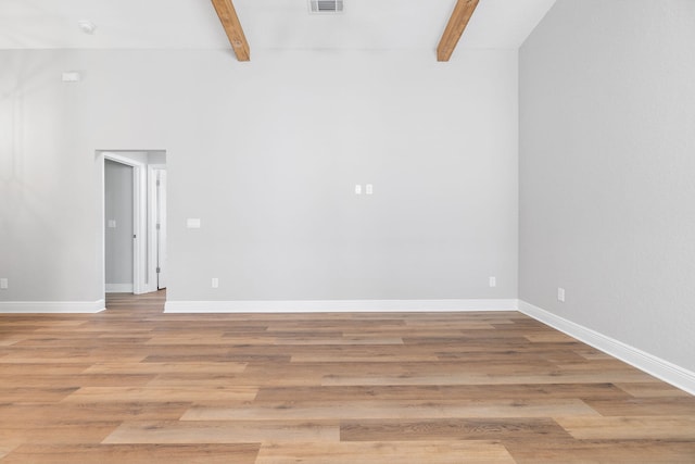 spare room featuring beamed ceiling and light hardwood / wood-style floors